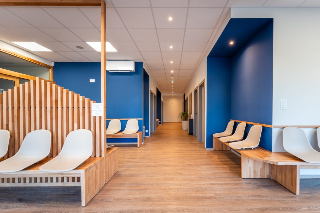 Salle d’attente de l’Institut de Chirurgie Orthopédique des Vosges avec mobilier bois et chaises design